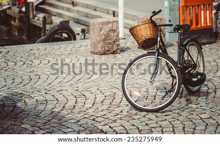Vintage Bicycle With Basket Parked On Sidewalk. Bike Parking In Big City. Toned Instant Photo