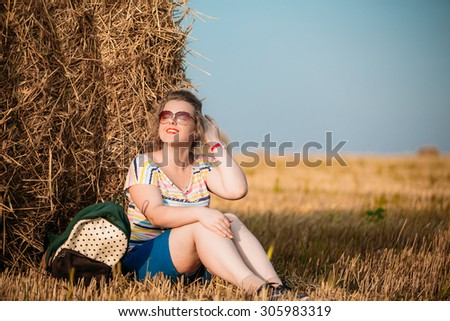 Beautiful Plus Size Young Woman In Shirt Posing In Summer Field Meadow On Hay Bales At Sunset Background