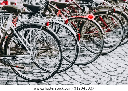 Parked Bicycles On Sidewalk. Bike Bicycle Parking In Big City. Red, Black, White and Red Colors Photo.