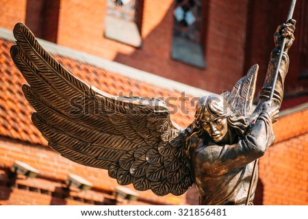 Statue Of Archangel Michael With Outstretched Wings, Thrusting Spear Into Dragon near Red Catholic Church Of St. Simon And St. Helena On Independence Square In Minsk, Belarus