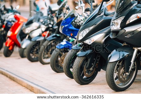 Motorbike, motorcycle scooters parked in row in city street. Close up of wheel