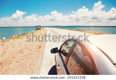 Car Driving Across Ocean By The Road