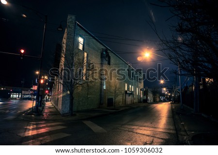 Dark city street corner and alley with an industrial building at night