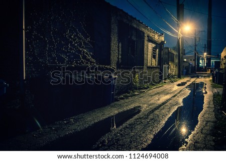 Dark, gritty and wet industrial city alley at night after rain