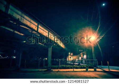 Dark and eerie urban city street corner with a vintage railway bridge and the moon at night