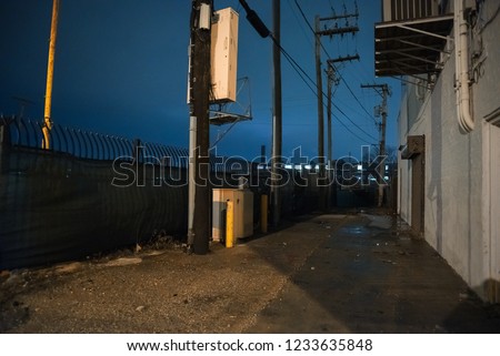 Dark and scary urban city alley with a fence at night