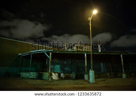 Scary industrial urban street city night scene with decaying loading docks by vintage factory warehouses