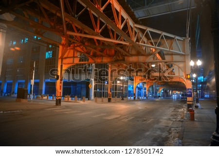 Deserted downtown city street intersection under a vintage railroad train subway bridge at night in Chicago