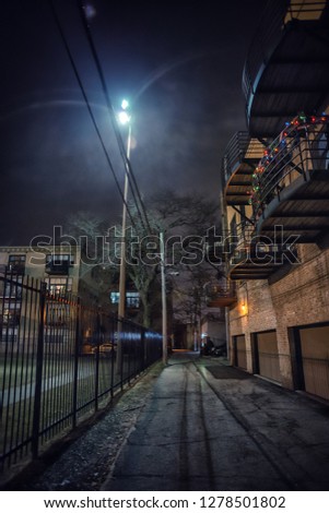 City alley with a fence and balconies in Chicago at night
