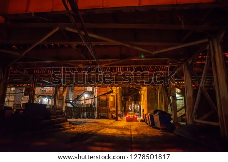 Scary Chicago alley under a vintage railroad bridge with a car at night