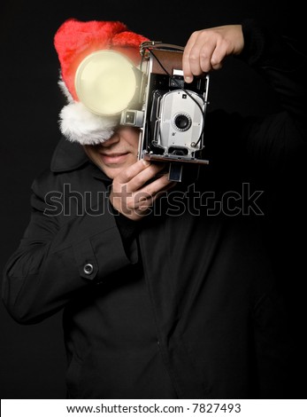 Photographer wearing santa hat taking a picture with vintage camera and flash