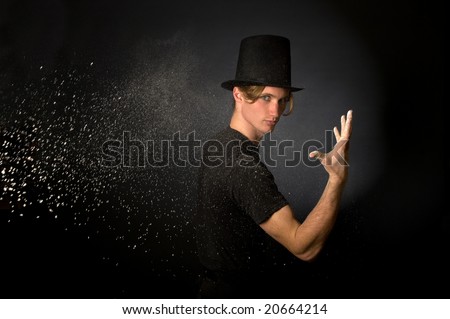 Young male magician throwing magic powder
