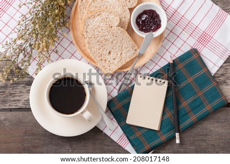 Memo pad with bread and a cup of coffee on table.