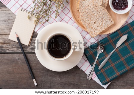 Memo pad with bread and a cup of coffee on table.
