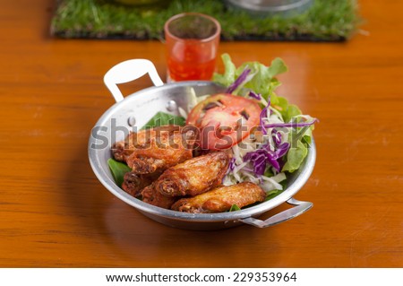 Fried chicken wings with vegetable in steel bowl.