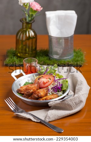 Fried chicken wings with vegetable in steel bowl.