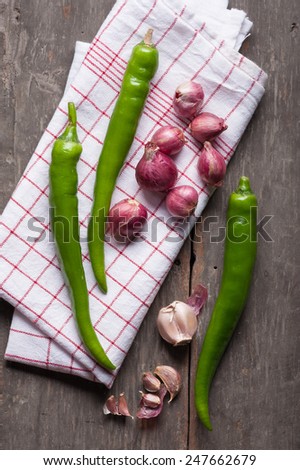 Shallots (red onion), garlics and green chilli set up on wood table with low key scene.