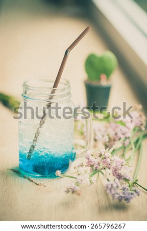 Blue Italian soda on wood bar in cafe with film filter effect