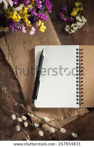 Small notepad with pen on rustic wood background with low key scene.
