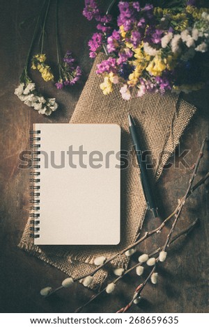 Small notepad with pen on rustic wood background with film filter effect