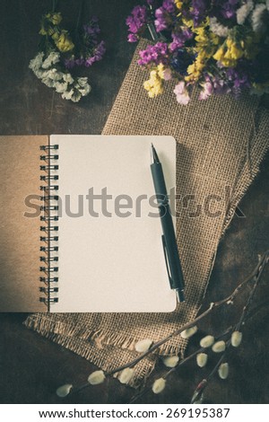 Small notepad with pen on rustic wood background with film filter effect