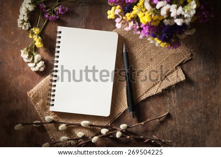 Small notepad with pen and pencil on rustic wood background with low key scene.