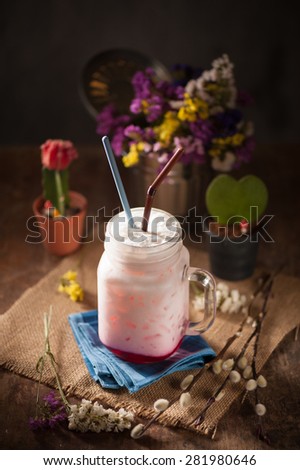 Fresh milk with red syrup on wood table in cafe with low key scene