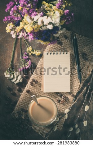 Notepad with pen, a glass of Thai tea on rustic wood background with film filter effect