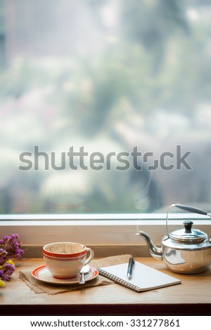 Coffee cup and opened notebook on wood bar at coffee shop in morning time of winter season