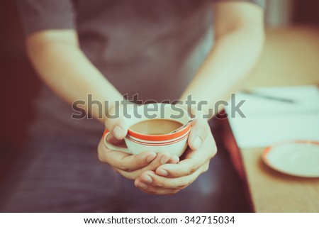 The man wearing grey t-shirt holding coffee cup in his hand in afternoon time