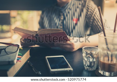 Sunday morning lifestyle scene of young hipster asian woman reading book in cafe with. Weekend activity or hobby concept with vintage filter effect