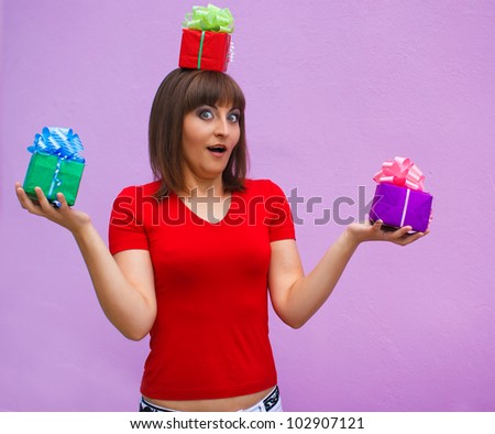 surprised woman with open mouth holds a box with gifts on his head on a lavender background