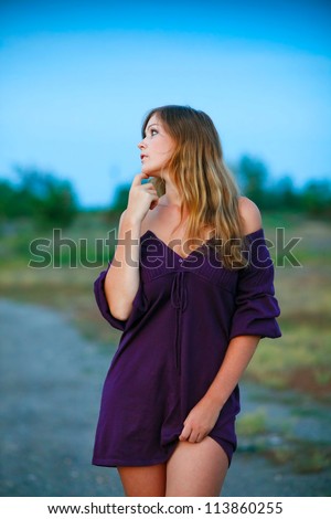 young woman knitted dress of purple on blue background with natural breasts and shoulders bare feet