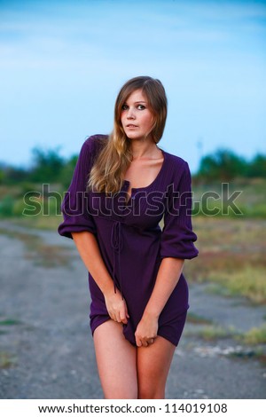 young woman knitted portrait dress of purple on blue background with natural breasts and shoulders bare feet
