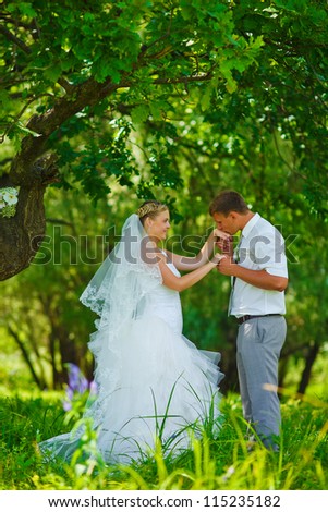 bride groom kissing hand of blonde bride, newlyweds couple are in a green forest in wedding summer