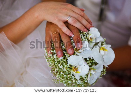 beautiful hands with rings of bride and groom on large red wedding bouquet