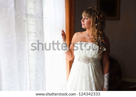beautiful young bride is at a wedding in the room by window