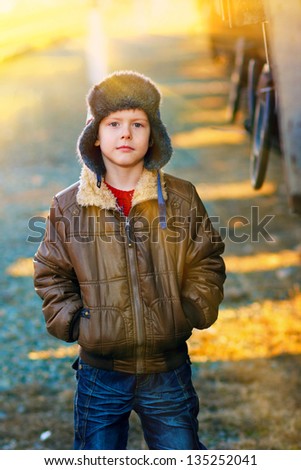 sunlight Boy homeless bum in brown jacket and a fur hat and crumpled jeans on the street near railway wagon