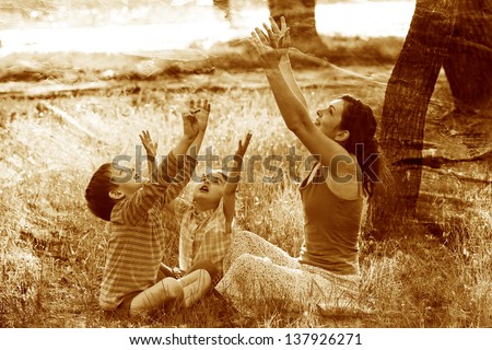 retro sepia photo, mom daughter son sitting outdoors picnic meditate stretching out their hands sun sunset