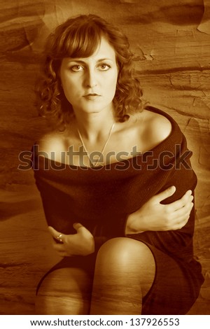 retro sepia photo curly girl woman in a brown dress sits near the old green wall