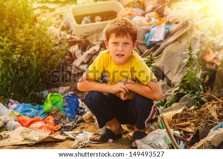 sunlight german homeless baby boy squatting on a rubbish dump in yellow t-shirt with tousled hair