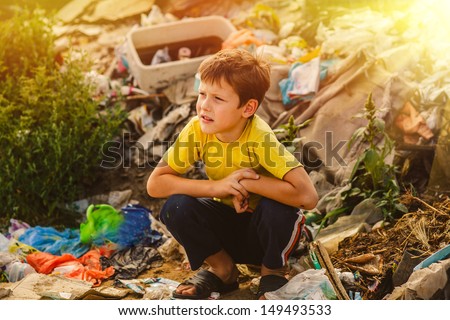 sunlight german homeless baby boy squatting on rubbish a dump in yellow t-shirt with tousled hair