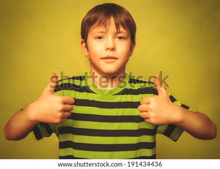 blonde boy kid in shirt holding thumbs up, showing sign yes emotion on a green background gray large cross processing retro