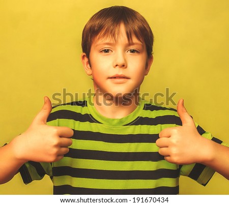 blonde boy kid in shirt holding thumbs up, showing sign yes emotion on a green background large cross processing retro