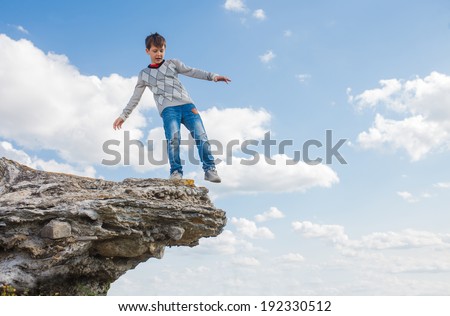 teenager acrophobia boy man stands on the precipice of a cliff height and fear of heights on a background of blue sky
