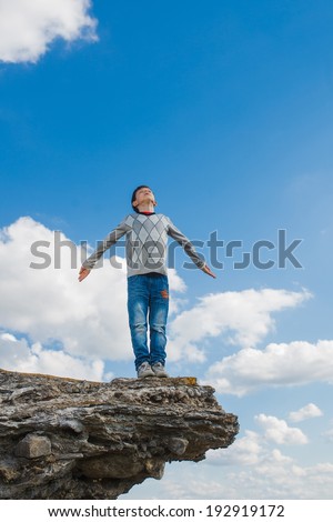 teenager suicide acrophobia boy man stands on precipice cliff height and fear heights on a background of blue sky