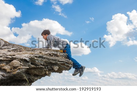 acrophobia teenager boy man stands on the precipice of a cliff height and fear of heights on a background of blue sky
