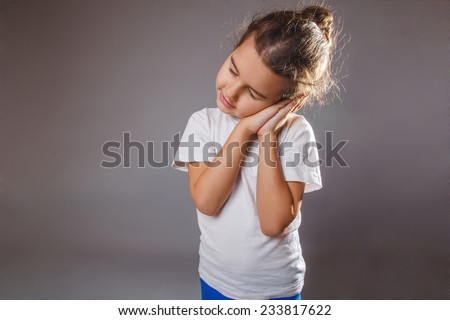 girl sleepwalking smiling in his sleep on a gray background put her hands on face