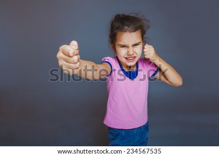 girl getting angry fist shows on a gray background