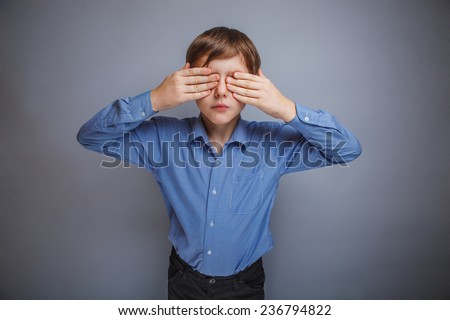 boy in shirt eyes closed hands on a gray background